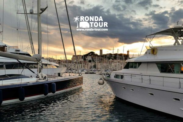 Vue de la vieille ville de Cannes depuis le port entre deux yacht. Filigrane avec le logo de Ronda Tour et son adresse web www.ronda-tour.com sur la photo.