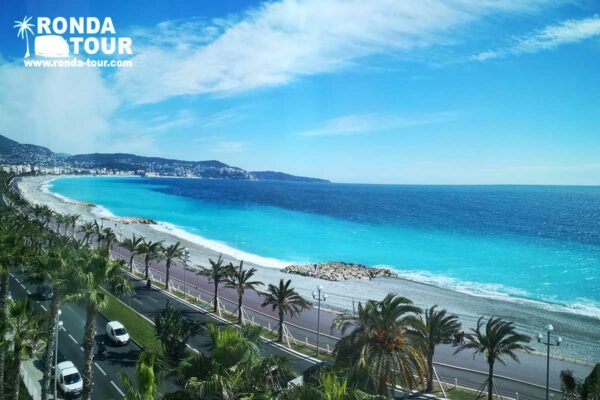 Promenade des Anglais à Nice avec une magnifique eau bleu turquoise et bleu marine. Filigrane avec le logo de Ronda Tour et son adresse web www.ronda-tour.com sur la photo.