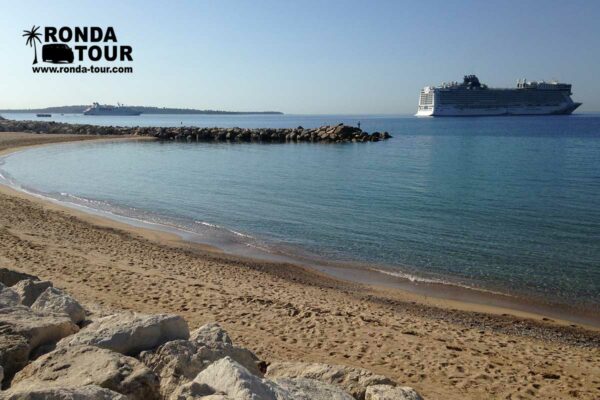 Bateau de Croisière dans la baie de Cannes. La vue est depuis la plage, la mer méditerranée est calme comme un lac. Filigrane avec le logo de Ronda Tour et son adresse web www.ronda-tour.com sur la photo.