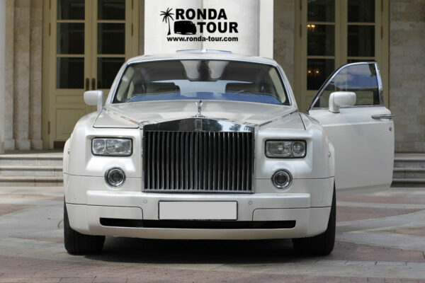 Rolls Royce blanche avec la portière du chauffeur ouverte. Filigrane avec le logo de Ronda Tour et son adresse web www.ronda-tour.com sur la photo.