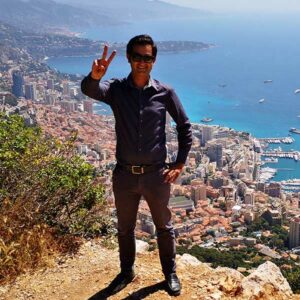 Benjamin, Fondateur de Ronda Tour à Cannes sur la Côte d'Azur en France pose sur un Rocher qui surplombe Monaco la France et l'Italie